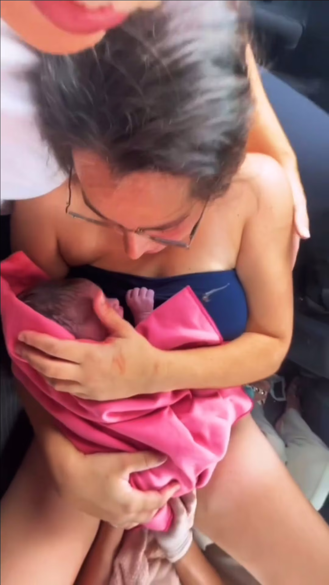 Mãe segurando recém-nascido dentro de carro após parto improvisado